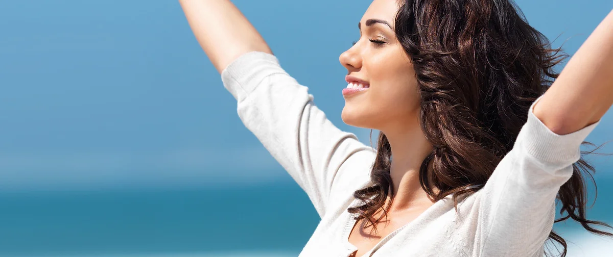 A happy woman throwing her arms up in the air after therapy