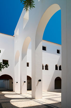 Large white arches on the hotel grounds, sitting on tiled floor. Both showing the effect of the sun shadows. 