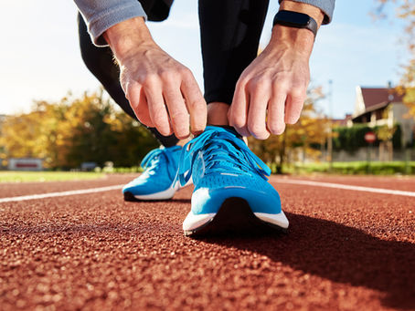man about to run a sprint on the track, tying his shoes together to get ready.