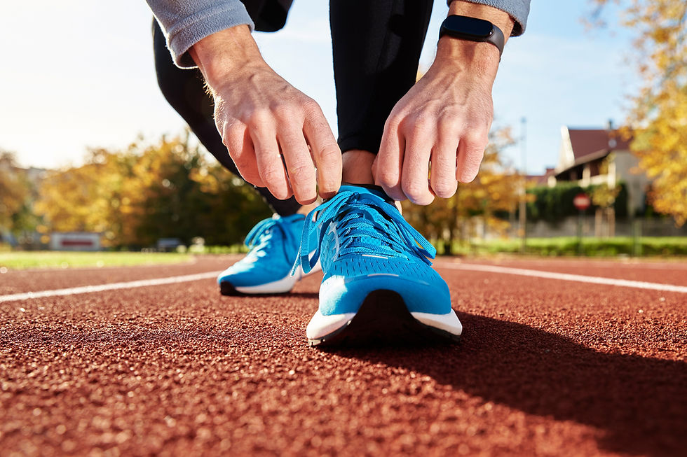 man about to run a sprint on the track, tying his shoes together to get ready.