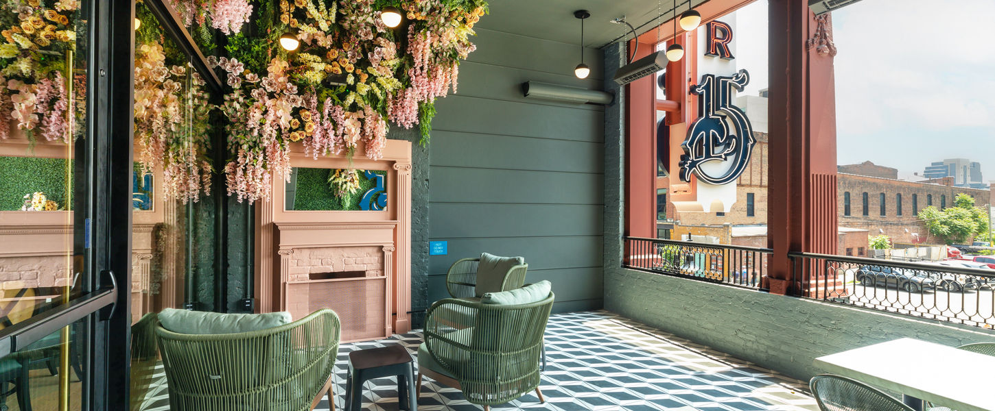 A photo of the interior of number 15 louisville showing green chairs, green walls, a pink fireplace, and pink flowers climbing up the walls in one of the corners.