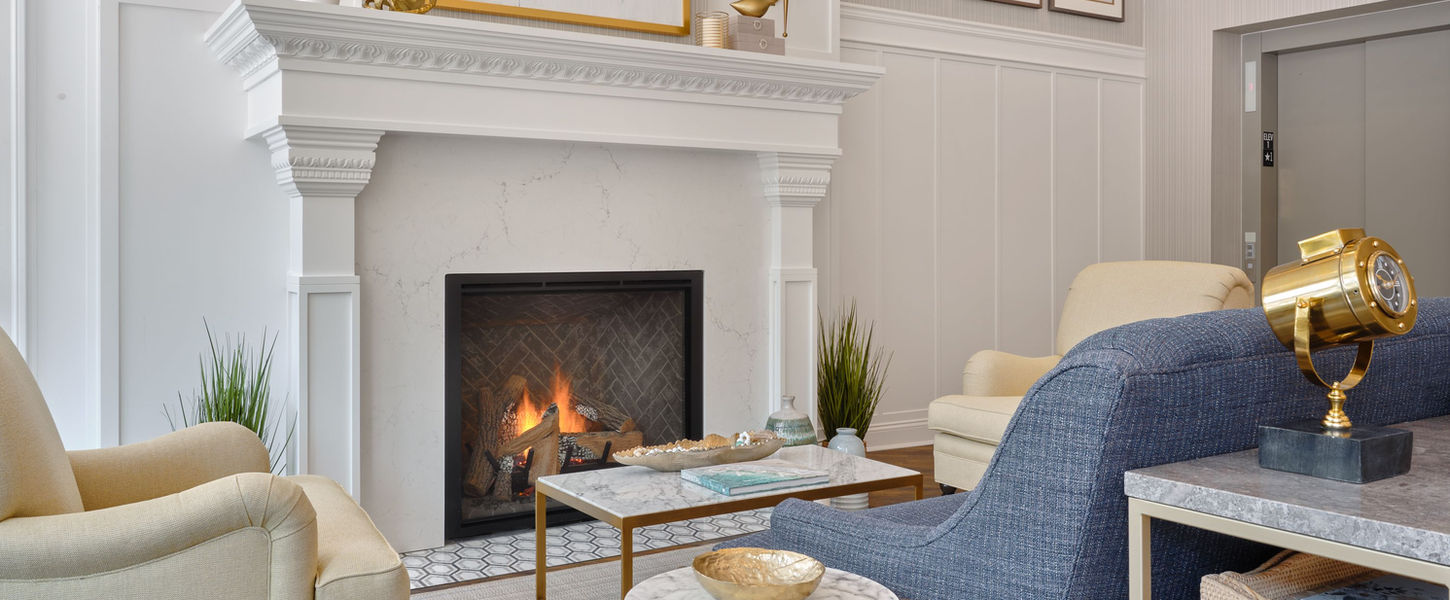 Interior photo of the northport hotel showing a fireplace and three comfy armchairs. 