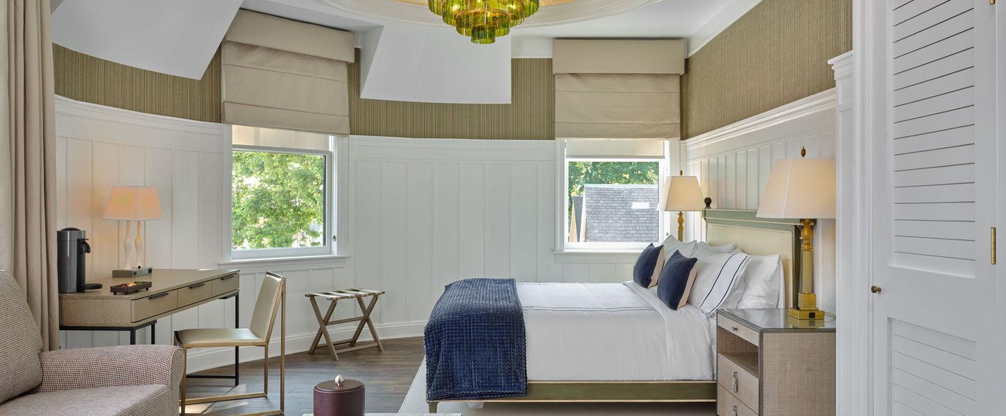 A photo of the interior of the northport hotel showing a bedroom with beige and olive green accents.