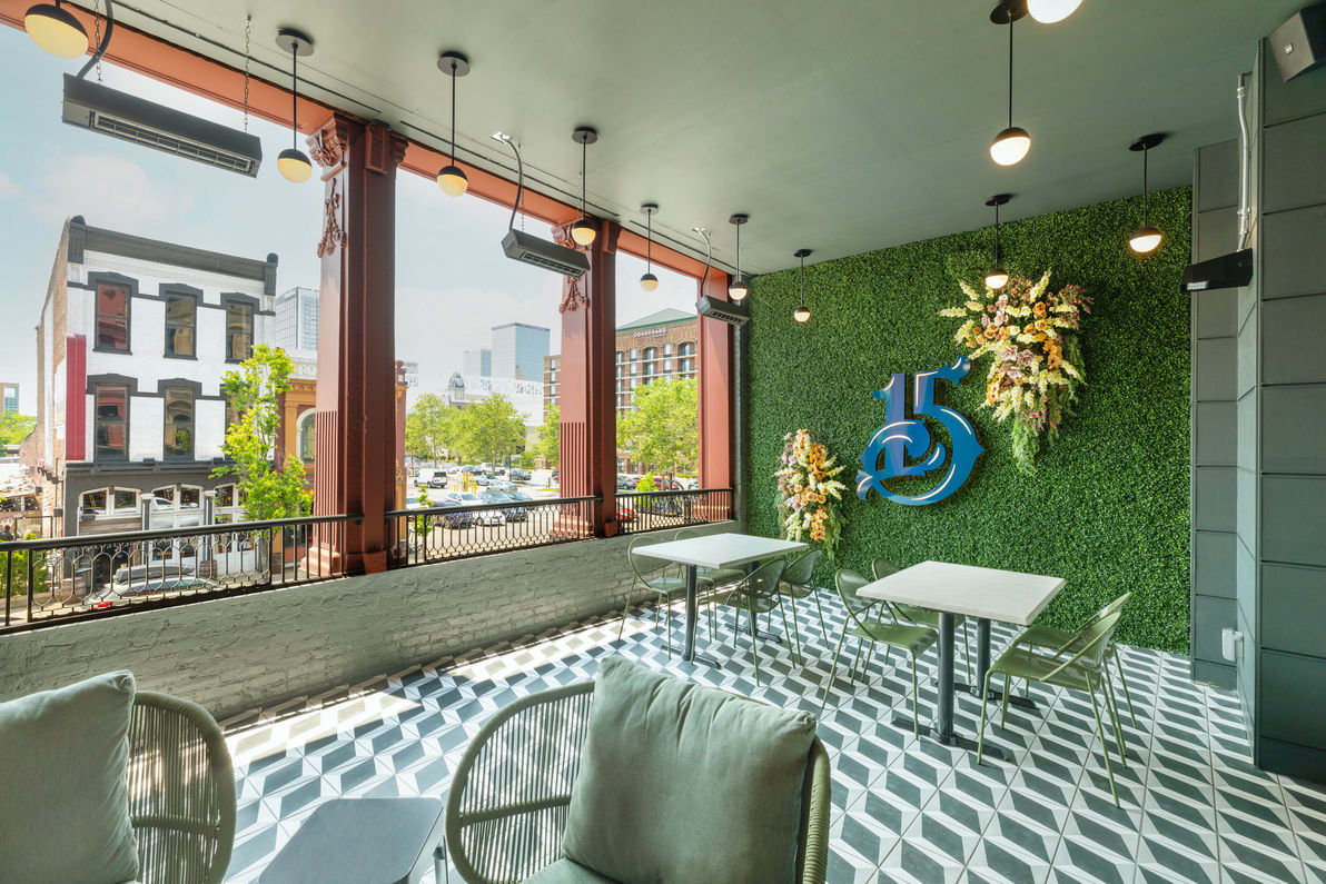 A photo of the interior of number 15 louisville showing green chairs, and a green plant wall with a large, blue number 15 on it.