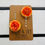 Thumbnail: Orange pompom flower hair clip set of 2. set on a brown card backing. front view