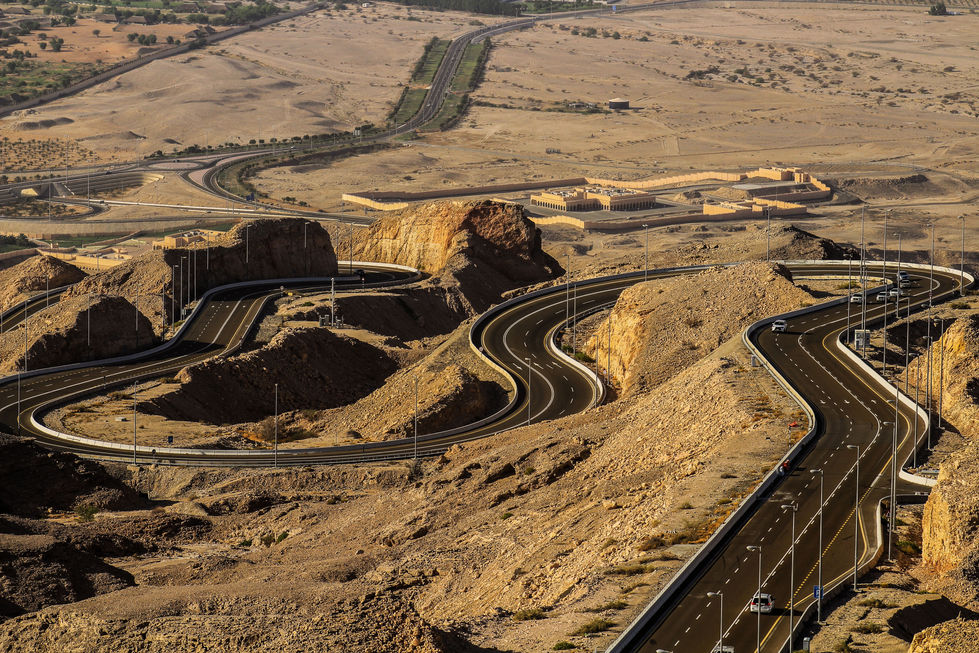 Curving asphalt roads through golden dunes in the UAE desert – human design meets harsh terrain