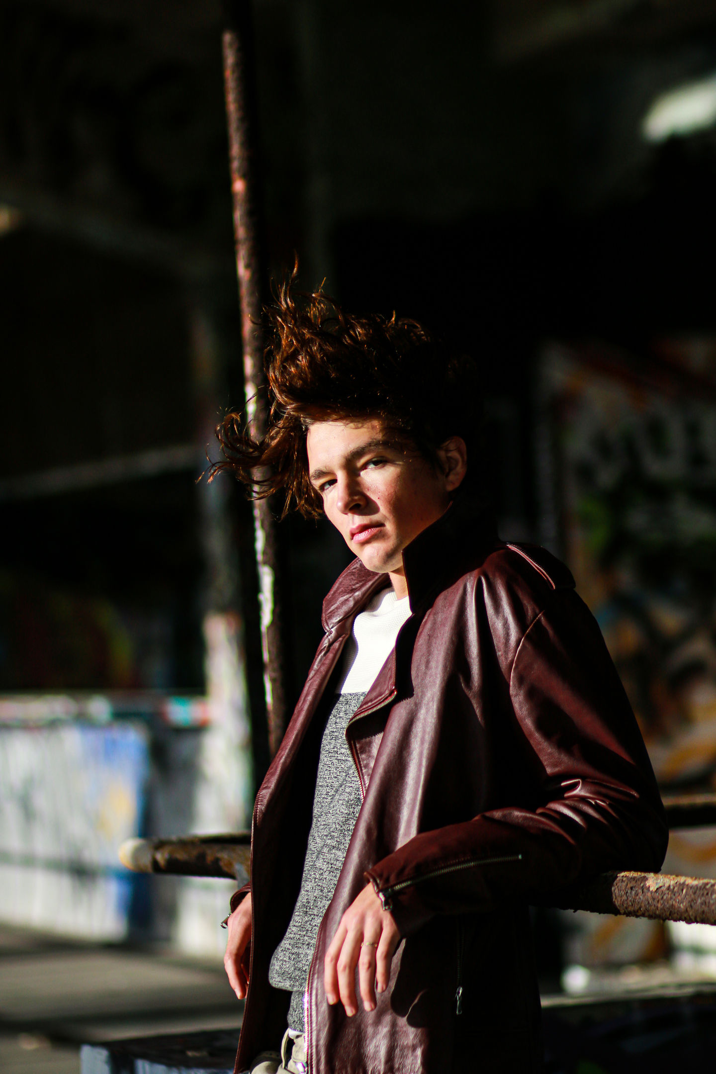 Male model in silk burgundy shirt under moody lighting – cinematic urban portrait