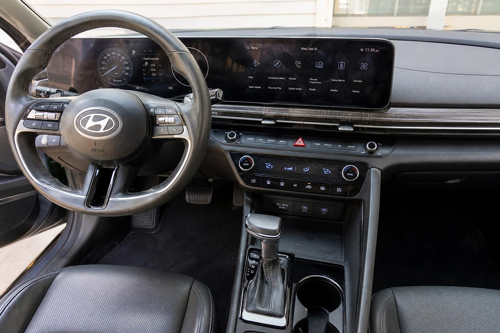 Hyundai car interior with steering wheel, digital dashboard, large infotainment screen, gear shifter, and climate controls displayed.