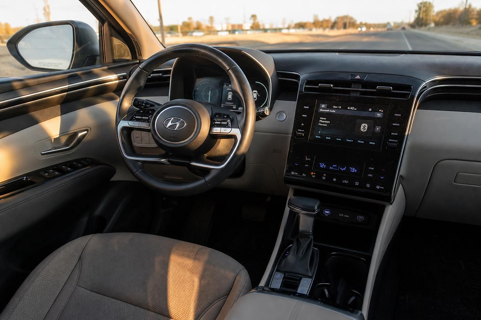 Hyundai car interior with steering wheel, touchscreen, and tan seat, driving on a sunny road at sunset.