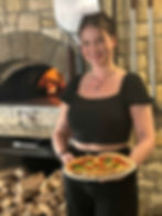 The Birdwood's Waitress holding a delicious looking Wood-Fired Pizza in front of a wood fire pizza oven