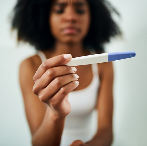 woman looking at a purple pregnancy test