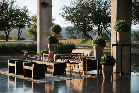 a patio with a couch and chairs and potted plants