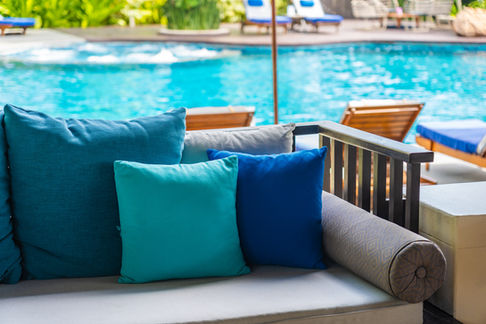 blue and white pillows on a couch in front of a pool