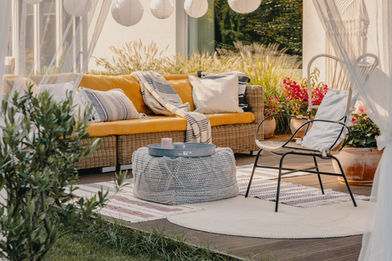a wicker couch with a yellow cushion sits on a patio