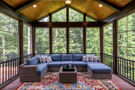 a screened in porch with a couch and view of the woods