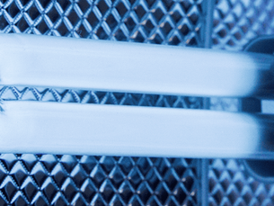 Close-up of a glowing fluorescent tube against a textured, diamond-patterned blue background, emitting a cool, industrial feel. The image represents UV lights for HVAC.