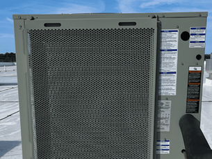 Rooftop HVAC unit with detailed labels, surrounded by similar equipment. Set against a clear blue sky, creating a calm, industrial scene. HVAC system installed by The Service Pros in Tampa Bay.
