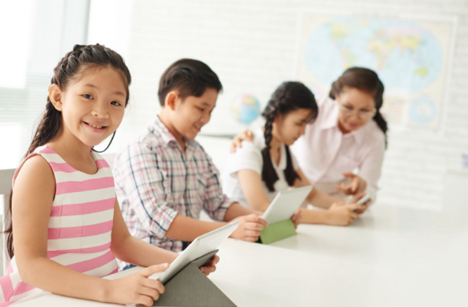 Happy students in a classroom as a teacher checks up on them