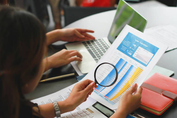 Businesswoman examining a financial report with a magnifying glass, representing Payment Removal Services.