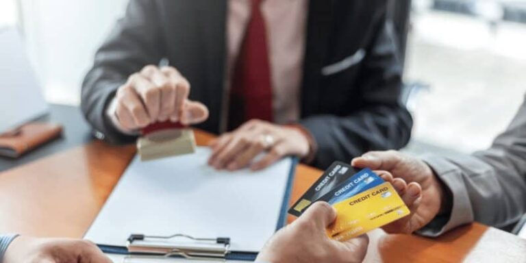 A group of business people at a table, each holding credit cards, focused on credit repair strategies.