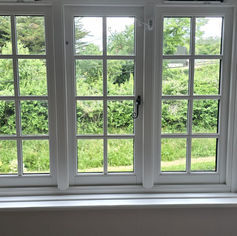 Clean white casement window with outdoor garden view