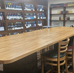 Long wooden tasting table with chairs in a wine cellar.
