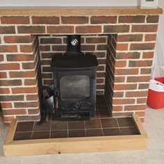 Wood burning stove in a brick fireplace with cleaning supplies