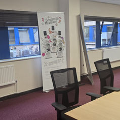Clean office meeting room with black mesh chairs and tables.