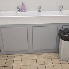 Clean commercial restroom with multiple sinks and bins.