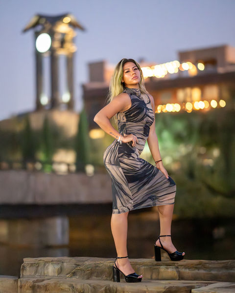 Woman in patterned dress posing on outdoor steps at night