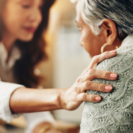 A compassionate woman gently holding the shoulder of another woman in need of emotional and spiritual healing through faith in Jesus.