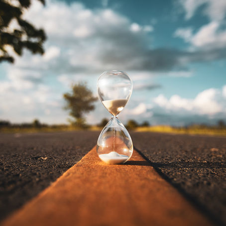 An hourglass resting in the middle of a quiet road, symbolizing patience, trust, and the beauty of waiting on God’s perfect timing.