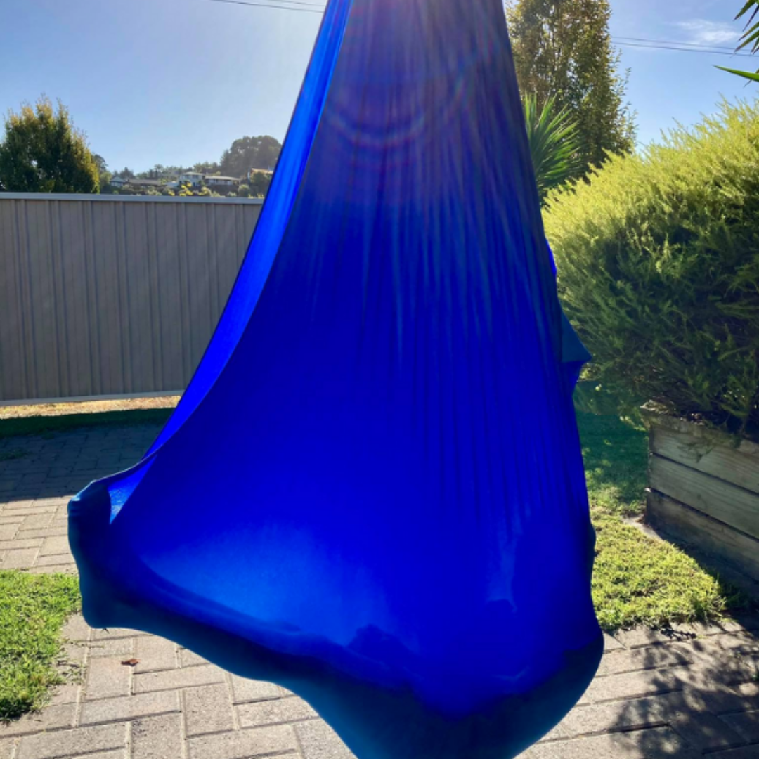 Blue lycra sensory swing hung outside with child swinging