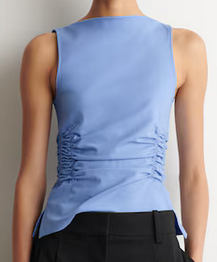 Back view of a person wearing a light blue sleeveless ruched top and black pants against a plain white background