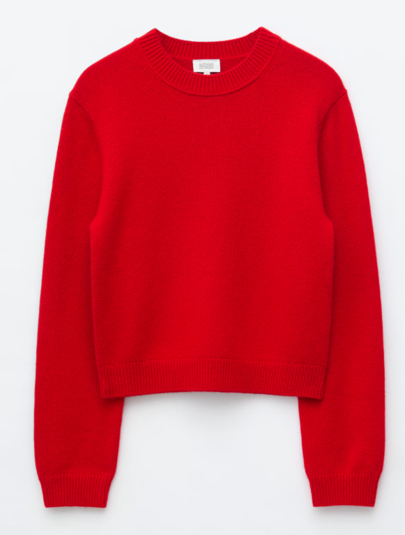 Bright red knit sweater with long sleeves and ribbed cuffs, laid flat on a white background with a small neck label.