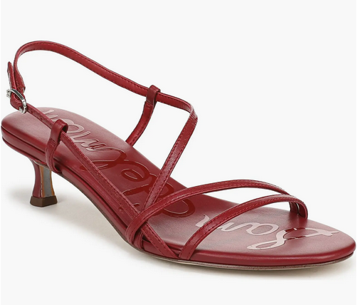 Red strappy sandal with a low heel, featuring visible cursive text on the insole. Set against a plain white background.
