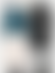 an outfit idea from Massimo Durri: off white flowing trousers, black loafers and bag, a blue cardigan, a long leather trench coat in black, golden earrings and sunglasses