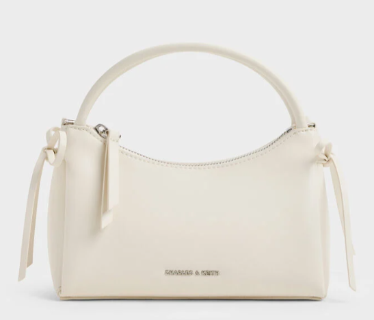 Cream Charles & Keith handbag with top handle and side ties on a white background, shown front view.