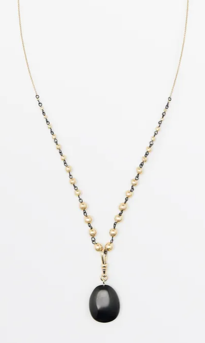Gold and pearl necklace with a black teardrop pendant on a white background