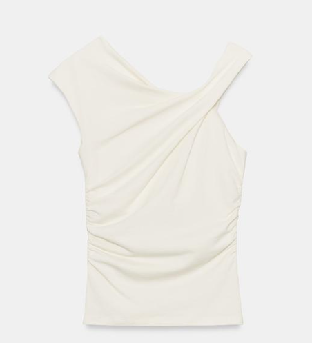 White sleeveless draped blouse with asymmetrical neckline on a plain light background