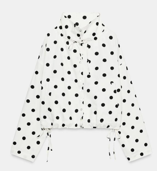 White hooded jacket with black polka dots, long sleeves, and drawstring ties on a plain light background.