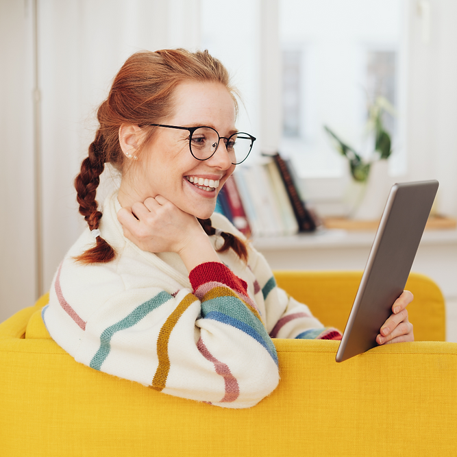 White woman with red hair and glasses sits on a yellow chair learning AI for editing