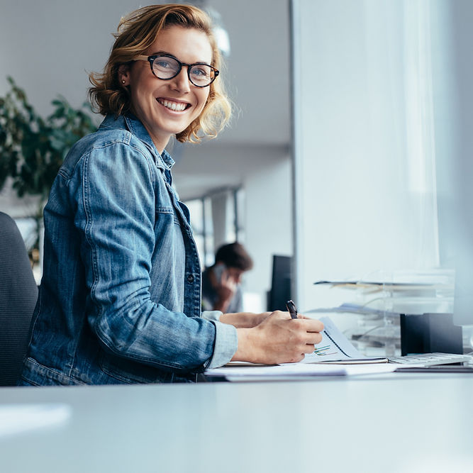 White woman with red hair and glasses sits on a yellow chair learning AI for editing