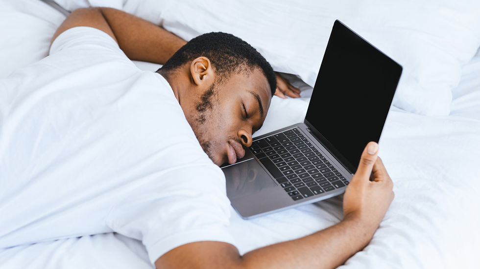 A person lies asleep on a bed while holding an open laptop.