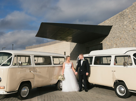 Newly-weds posing between two Coastal Kombi vans