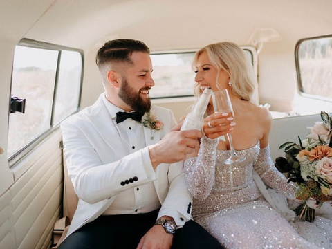 Newly-wed celebrating with champagne in a Coastal Kombi during their wedding