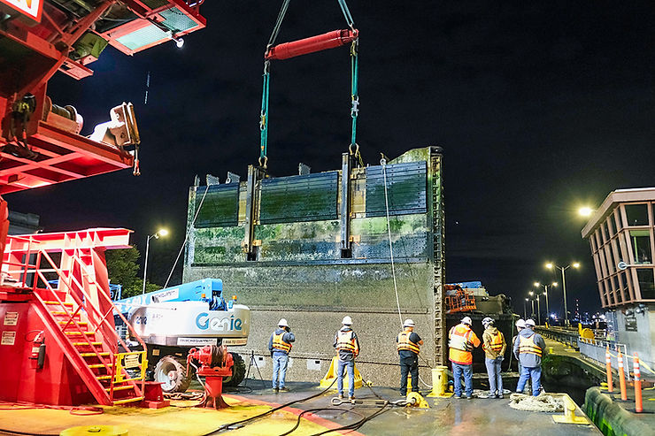A group of construction workers heavy lifting a miter gate on a jobsite.