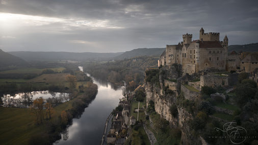 Castle on a cliff above a river under moody overcast light