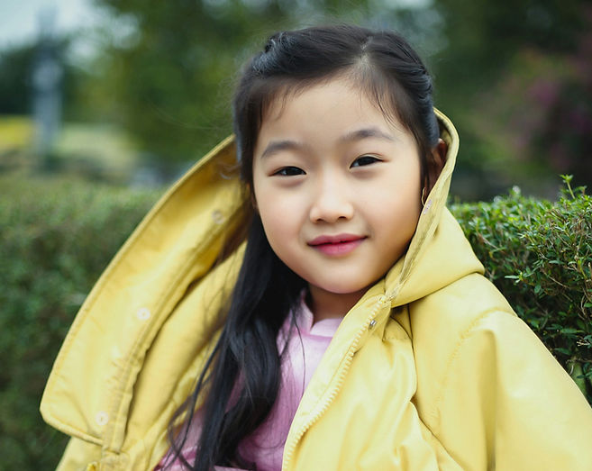a little girl in a yellow jacket sitting