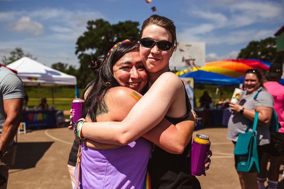 Friends in the LGBT+ community embrace, sharing a moment of love and unity amidst the first pride celebration in Brazoria County. 